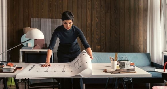 Maqueta arquitectónica sobre mesa junto a computadora portátil y taza de café.