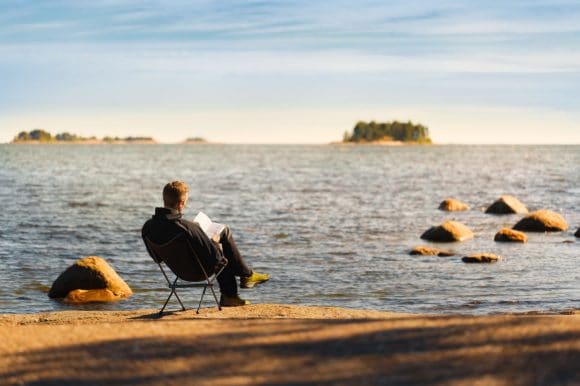 Hombre sentado en la playa leyendo
