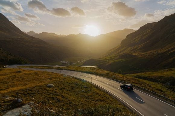 Carretera de montaña sinuosa con un automóvil al atardecer.