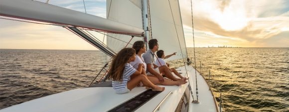 Familia navegando en un barco, con niños y adultos disfrutando juntos del paseo.