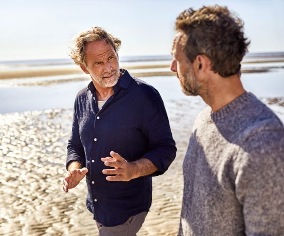 Personas conversando mientras caminan en la orilla del mar