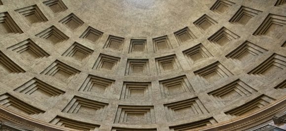 Vista interna de cúpula histórica com caixotões quadrados em padrão geométrico.