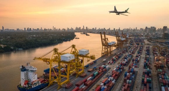 Avião voando sobre terminal de carga de contêineres