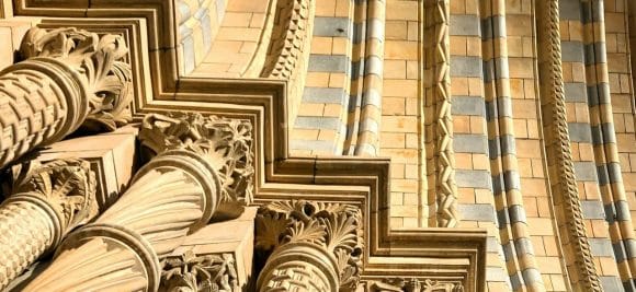 Detalhe arquitetônico em pedra dourada, mostrando colunas decorativas e arco.