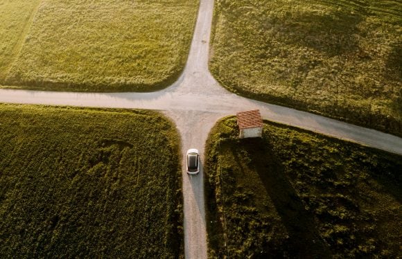 Carro em uma estrada rural se aproximando de um cruzamento