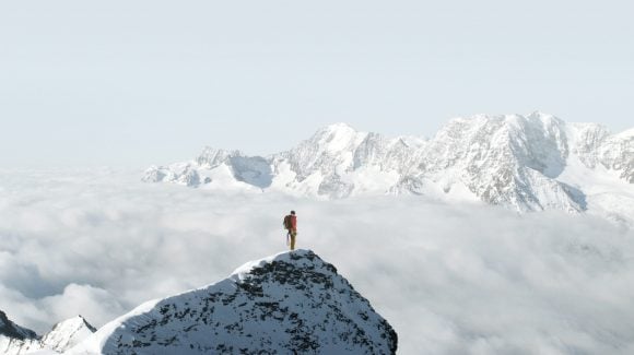 Person standing on a snowy mountain peak   