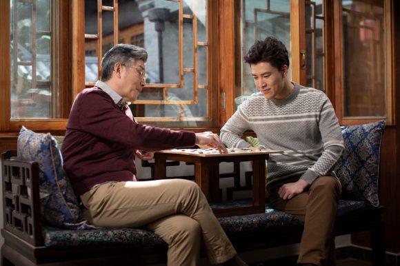 Asian father and son playing board game