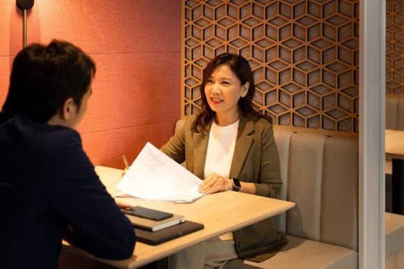 Two people in discussion in a office sitting on a sofa 