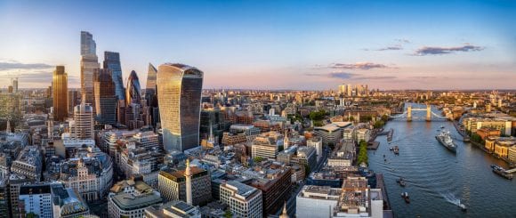 Sunlit view of London skyline along the river, featuring modern buildings and city landmarks.