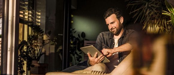 Men watching tablet seating on sofa