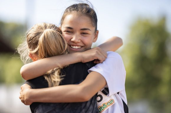 Auf dem Sportplatz auf der Rennbahn sind 4 Mädchen im sommerlichen Sportdress im Alter von ca. 13 Jahren bereit für den Startschuss für das Rennen am UBS Kids Cup.