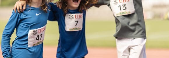 Foto vom UBS Kids Cup, 3 glückliche Kinder mit der UBS Kids Cup Startnummer