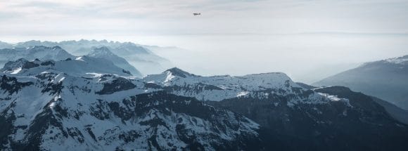 A small airplane passing by mountains in Switzerland