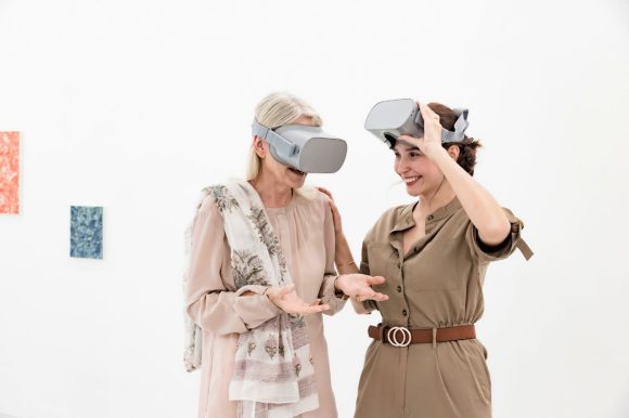 Two women with virtual reality goggles in a gallery