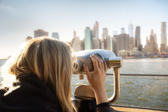 Mujer mirando a través de binoculares en el horizonte de Nueva York