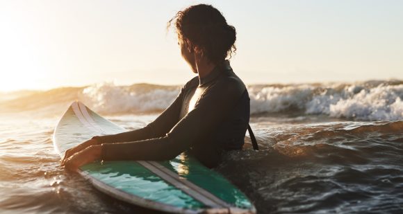 Mujer con tabla de surf en el océano