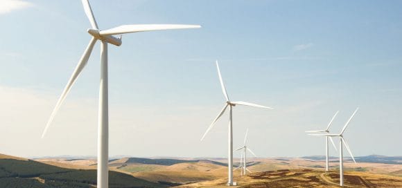 Campo verde de grandes turbinas eólicas. Esse relatório fala sobre 6 temas de investimentos sustentáveis.
