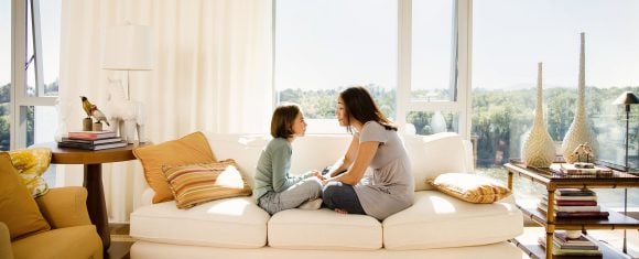 Uma mãe e sua filha sentadas em um sofá em casa