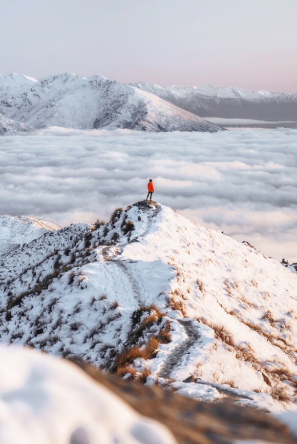 Um homem no pico de uma montanha com neve