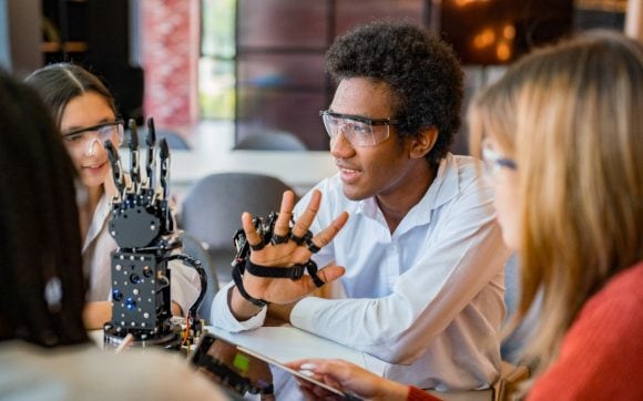 A group of people sitting and working with robot