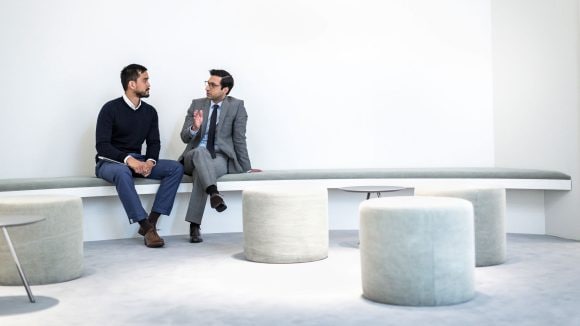Two businessmen sitting on a bench talking
