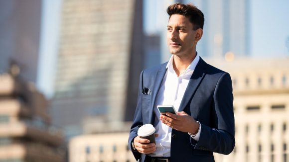 Man using phone and holding coffee