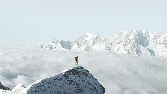 Person standing on a snowy mountain peak   