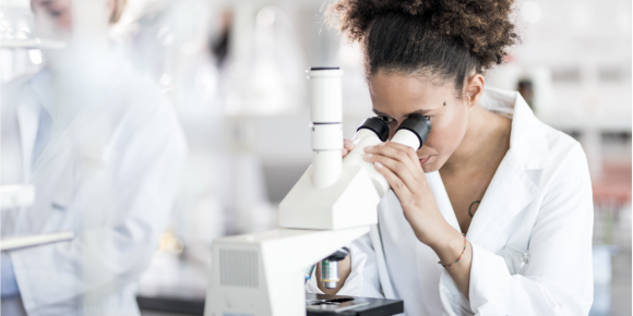 woman looking through a microscope
