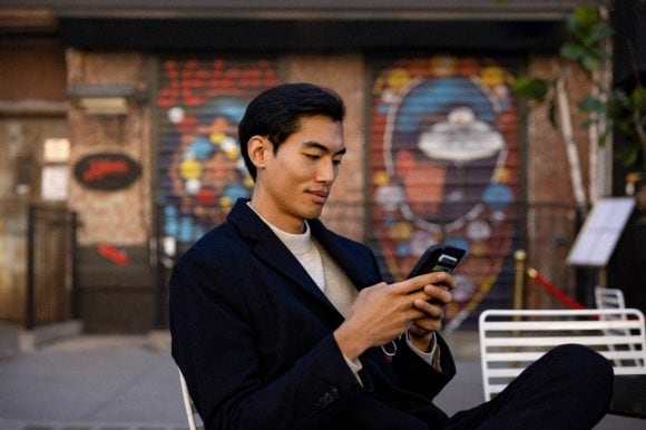man with smart phone sitting in cafe