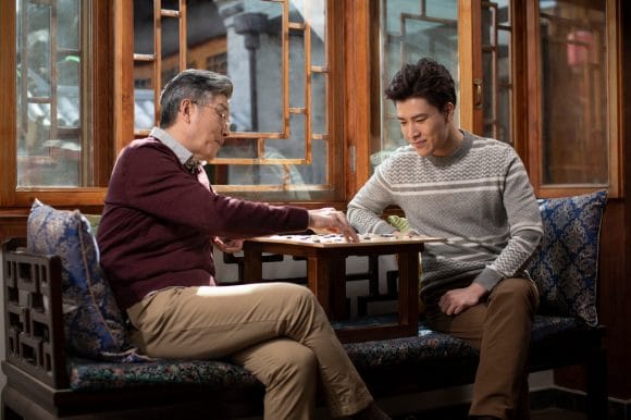Asian father and son playing board game