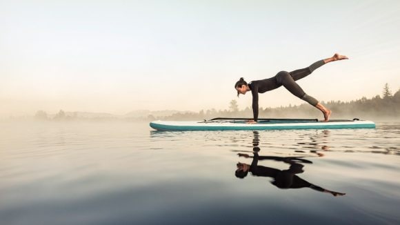 Womandoing yoga on surf board