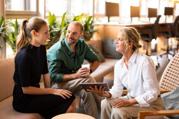 Three employees with tablet computer talking