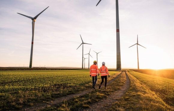 Two men walking in a field of windmill