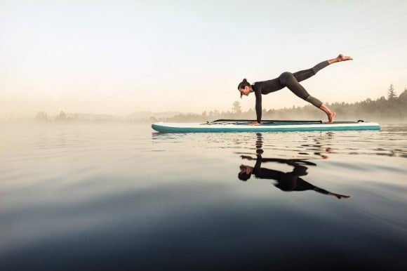Woman doing yoga on surf board
