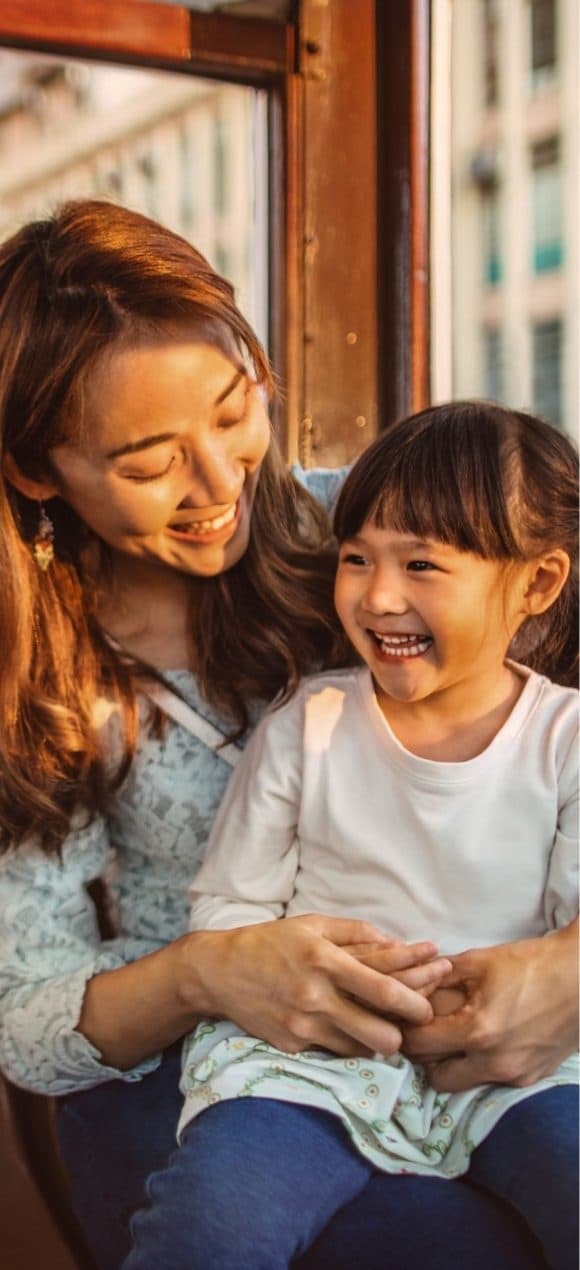A girl sitting on her mother's lap and laughing together