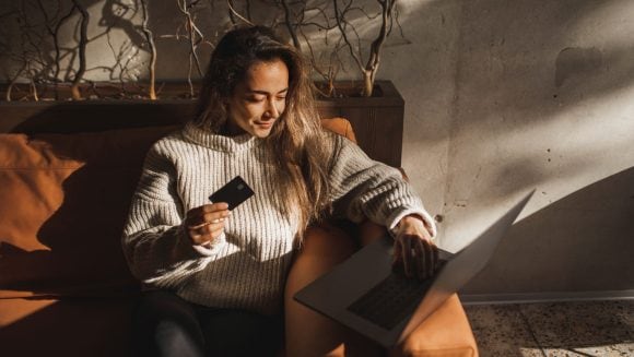 Woman holding credit card and laptop
