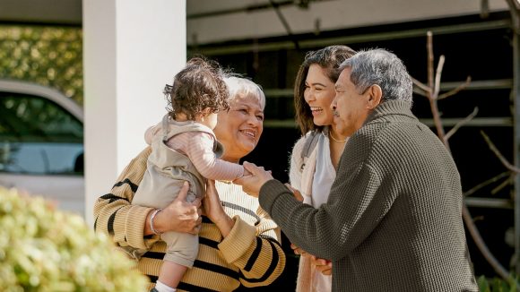 A family spanning three generations holds a baby.