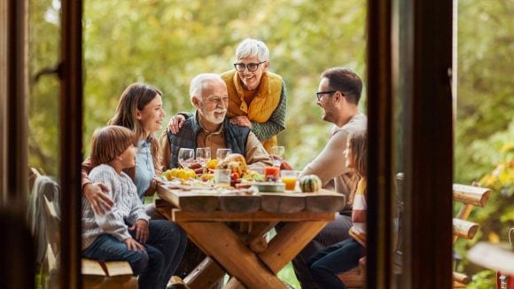 Three generation family eating dinner outside.