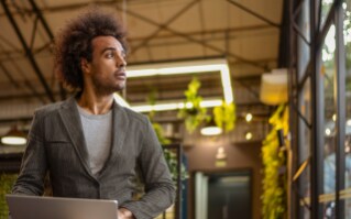 A woman sitting outside in the sunset, working on her laptop.