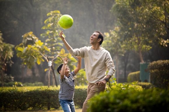 Father and son playing with ball in park