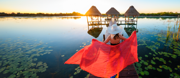 Woman playing with red sarong on a pier.