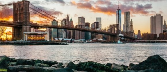 View of the Brooklyn Bridge spanning the East River at sunrise.