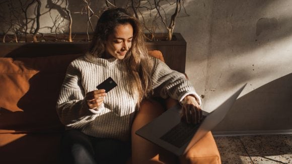 Woman holding credit card and laptop