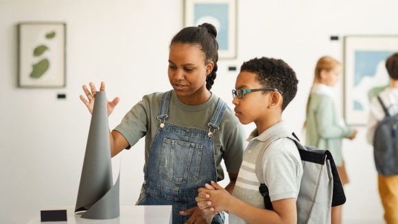 Group of diverse school-age children at an art museum interacting with an art display