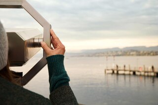 Woman looking through binoculars at lake