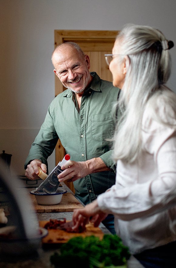 Man and woman preparing meal in kitchen.