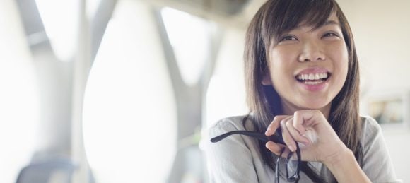 Smiling girl holding her glasses