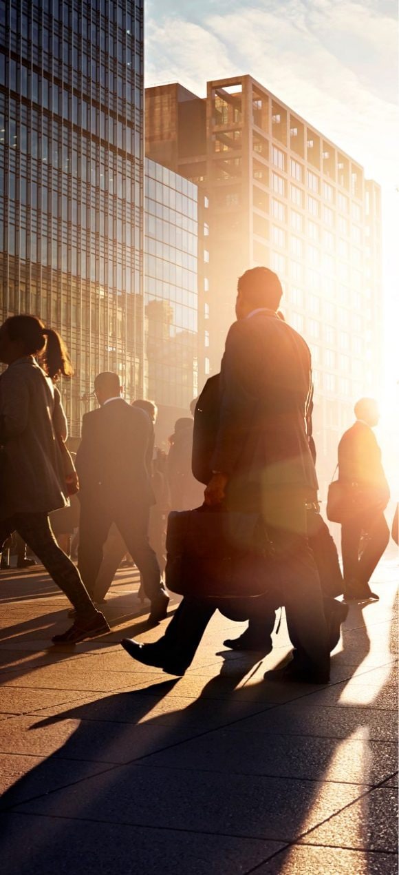 A group of businessmen and women walking down the street in morning sun