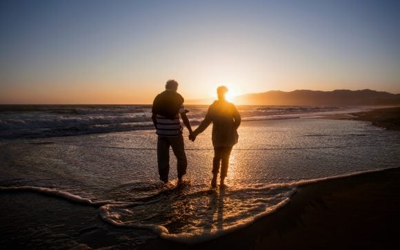 Couple walking on beach at sunset