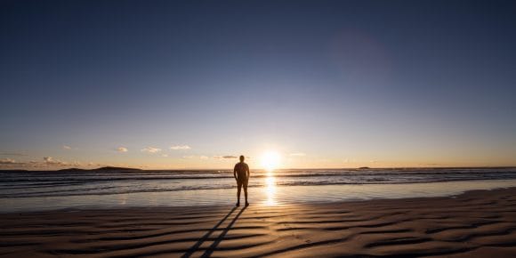 Man standing on beach looking at the sunset